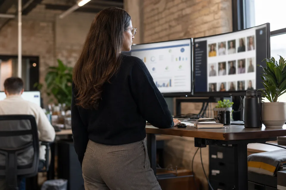 Brand manager comparing software dashboards on two monitors in a bright office