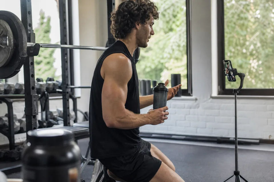 Fitness creator recording a vertical video with a phone on a gimbal in a home gym