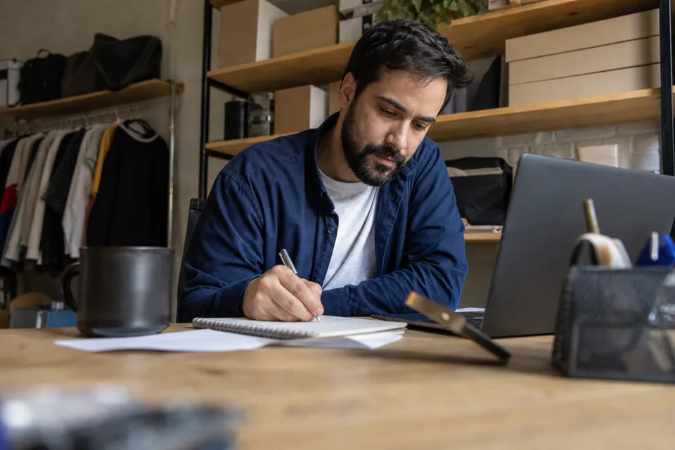 Founder planning a marketing budget at a laptop in a shop back office