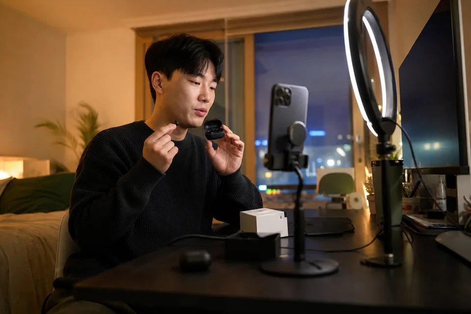 Creator filming a vertical gadget review at a desk with a ring light