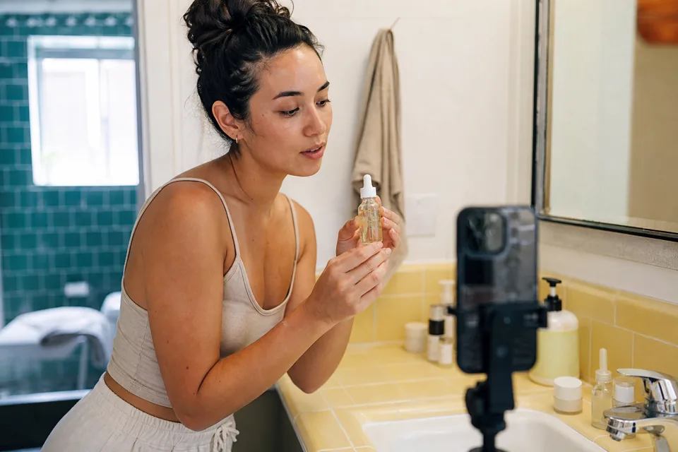 Creator recording a skincare video in a bright bathroom with a phone on a tripod